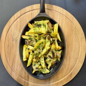 A hot frying pan with fried potatoes and mushrooms